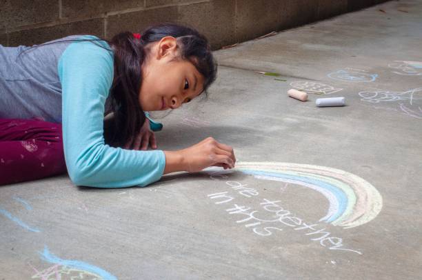 girl drawing with chalk on the sidewalk - child chalking imagens e fotografias de stock