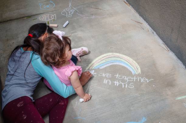 istock Girls drawing with chalk on the sidewalk 1218706419