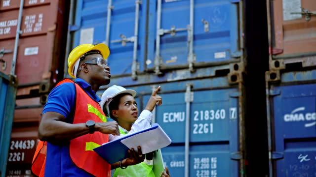 4K Black African Engineers Holding Clipboard Checking Shipping Cargo Freights In Front Of Cargo Containers In Shipping Container Yard