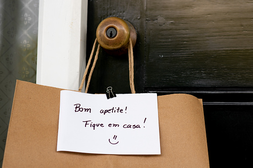 Food delivered at home with a note written in Portuguese 