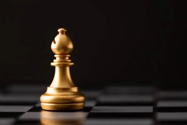 gold bishop on the chess board and black background