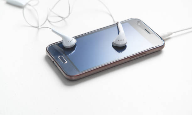 istock Smartphone with a earphones on white desk. 1218712547