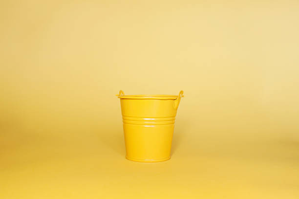 istock Empty yellow metal miniature bucket on a clean yellow flat background 1218712619