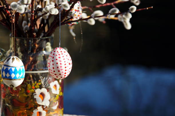Easter eggs decorations with narcissus (daffodil) flowers in a vase. Purple background with a vignette, much space for copy.