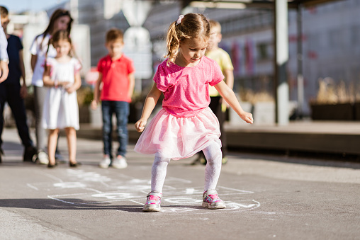 Children are playing hopscotch game on the street.