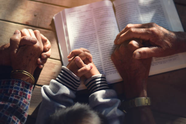 The boy prayed on the table. The family prayed together. stock photo
