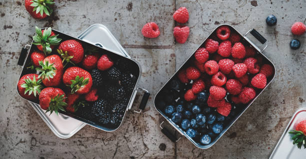 istock Fresh berries in metal lunchboxes over grey background, top view 1218718333