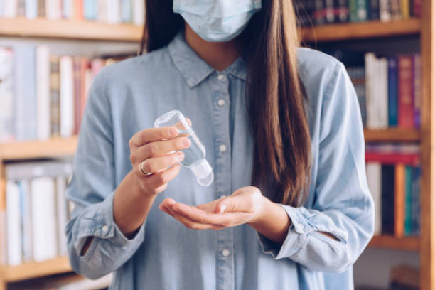 코로나 바이러스 개념. 그녀의 집에서 소녀는 코로나 바이러스로부터 보호하기 위해 그녀의 손에 살균 젤을 넣었습니다. 집에 머물 글로벌 전화. 스톡 사진