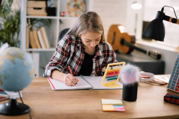 istock Cute little girl doing homework at her desk 1218718888