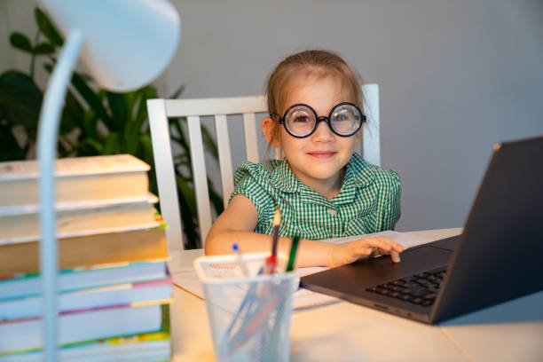 istock small girl in big glasses learning on laptop. 1218720193