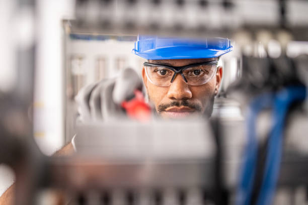 apprentice connecting wires in distribution board - blue helmets imagens e fotografias de stock