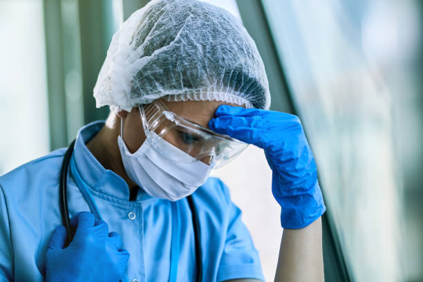 istock Exhausted female doctor having headache while working at clinic during coronavirus epidemic. 1218725036