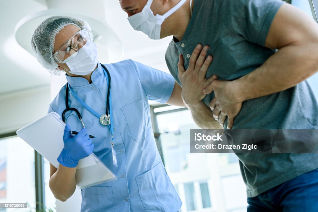 Don't worry, we'll try to help you! Female doctor with a patient who is complaining of chest pain during coronavirus epidemic. Chest Pain Stock Photo