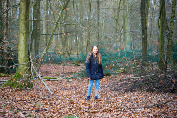 a girl stands in the forest and leaves fall on her