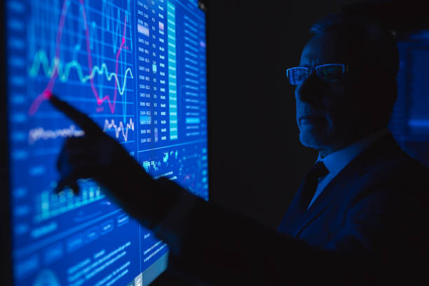 istock The old businessman working on the big blue screen with graphics 1218725700