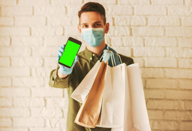istock Delivery man with smart phone and paper bags 1218726514