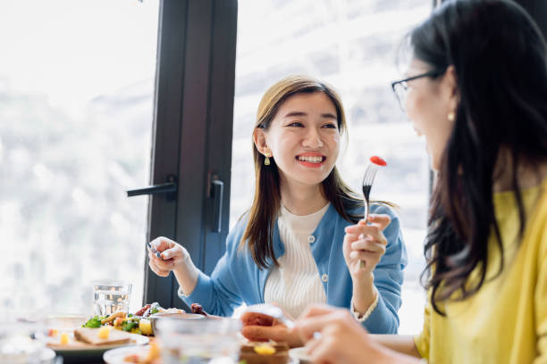 Asian female friends eating food together at cafe. Friendship, People, Dinner, China - East Asia, Shanghai, Eating, Two People, Restaurant chinese ethnicity china restaurant eating stock pictures, royalty-free photos & images