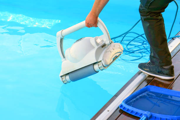 istock Hotel staff worker cleaning the pool. A pool cleaner holds a robot cleaner. 1218728334