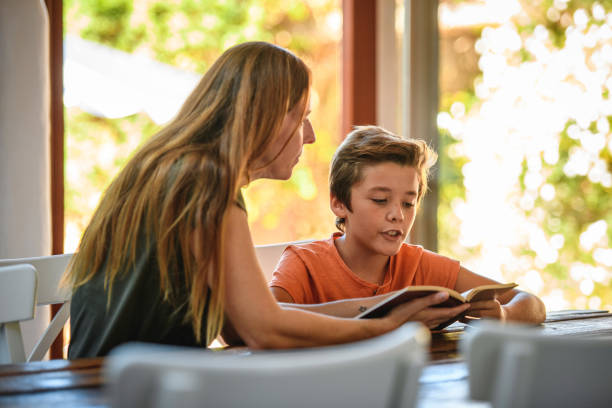 istock Smiling Mother Working with Young Son on His Reading 1218730400