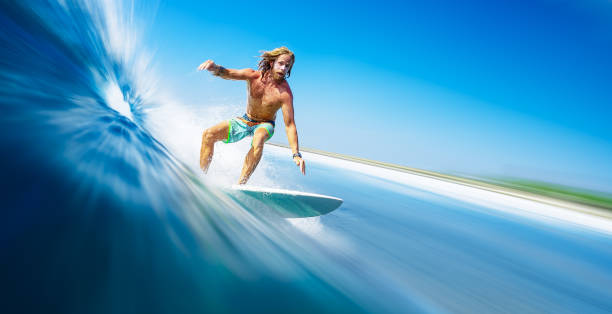 長い髪を持つ若い男のサーファーは、モルディブで速く、完璧な海の波をサーフィン - splashing maldives human hair spray ストックフォトと画像