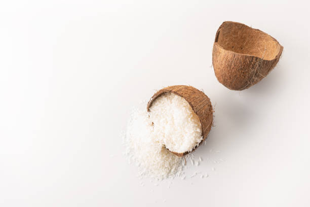 fiocchi di cocco si trova in un guscio di cocco, tagliato in due metà - powdered coconut foto e immagini stock