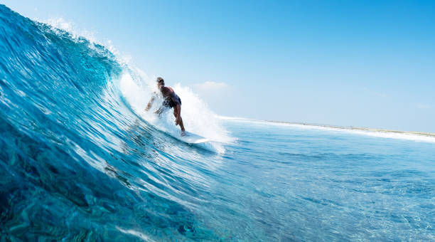 istock Young man surfs ocean wave in Maldives 1218732577