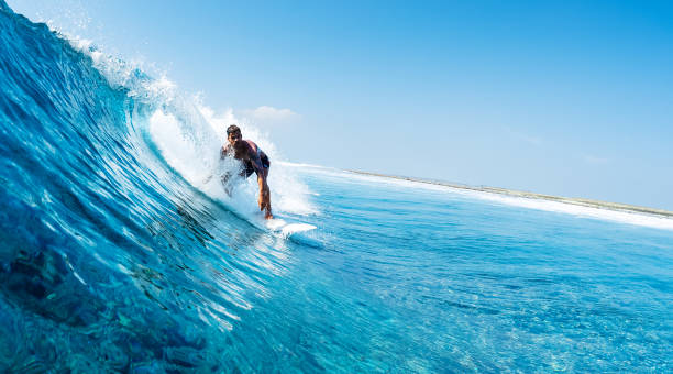 istock Young man surfs ocean wave in Maldives 1218732622