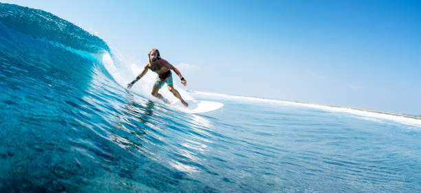 istock Young man surfs ocean wave in Maldives 1218732648