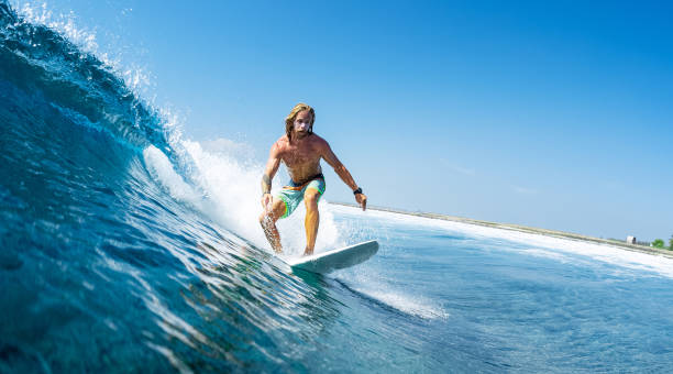 istock Young man surfs ocean wave in Maldives 1218732676