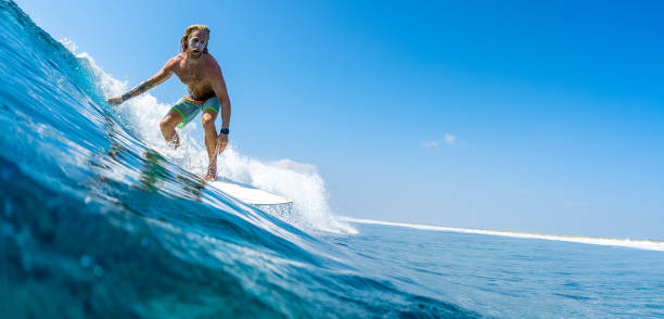 若い男はモルディブで海の波をサーフィン - splashing maldives human hair spray ストックフォトと画像