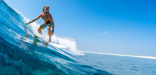 istock Young man surfs ocean wave in Maldives 1218732706