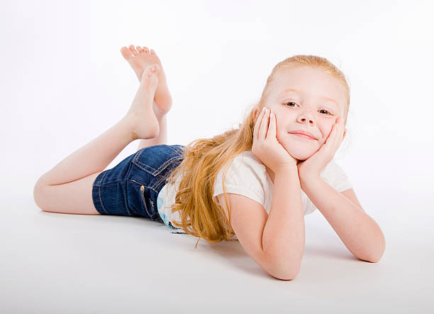 A happy young girl laying on a white background.