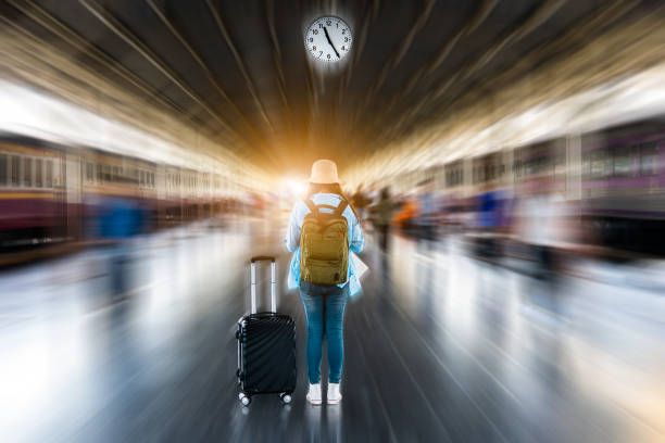 young solo woman backpacker tourist wait depart time clock to summer adventure voyage journey at train subway platform station with blurred motion speed movement abstract city busy crowded background - depart imagens e fotografias de stock