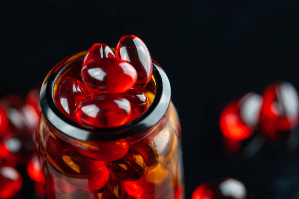 istock Red gel medical capsules on black background 1218742154