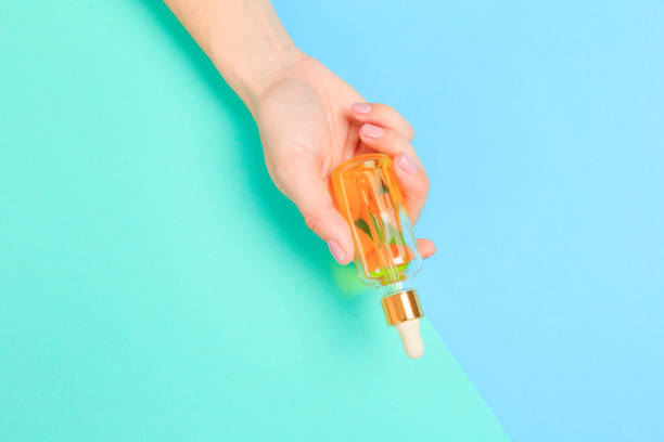 istock Beautiful young woman's hands with  oil bottle  on pastel background - Image 1218743589