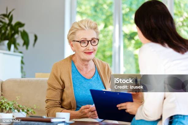Insurance Agent Explaining Agreement To Smiling Elderly Lady Stock Photo - Download Image Now