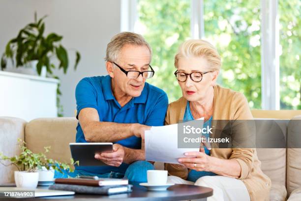 Retired Couple Watching Bills And Calculating Monthly Expenses Stock Photo - Download Image Now