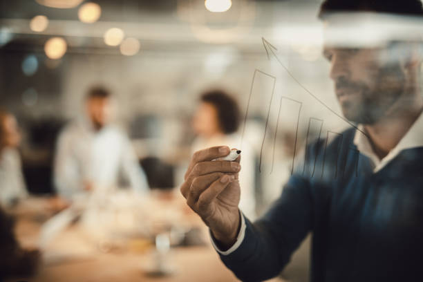 istock Close up of businessman drawing progress graph on transparent wipe board. 1218746424