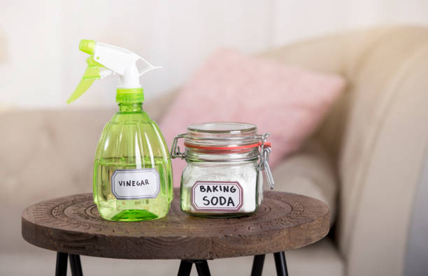 Using baking soda Sodium bicarbonate and white vinegar for home cleaning. White vinegar in spray bottle and baking soda in glass jar.