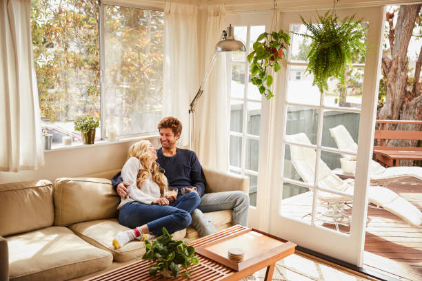 istock Laughing young couple sitting together on their sofa drinking coffee 1218751150