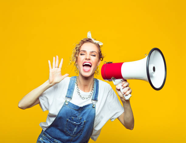 istock Young woman in dungarees shouting into megaphone 1218753203