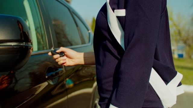 Woman with remote control device unlocking car door
