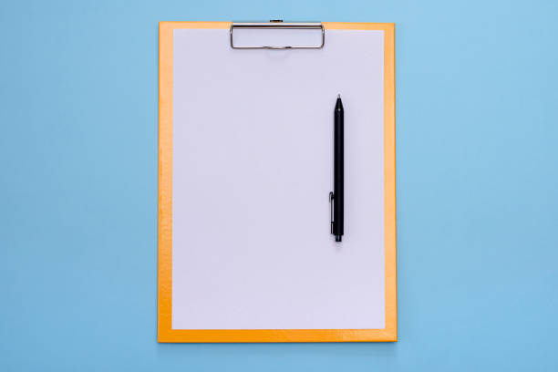 istock A yellow clipboard and a black pen with blank white paper on a blue background. 1218754537