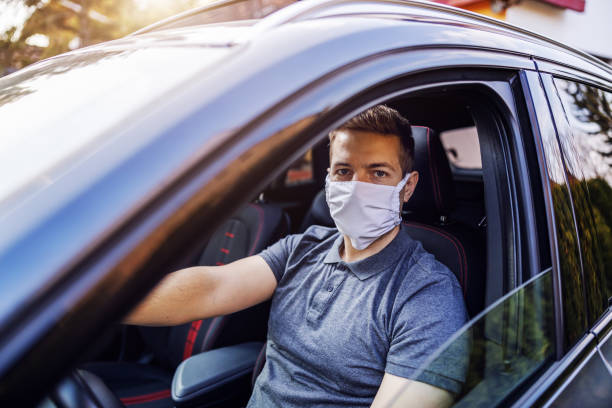 man with protective mask and gloves driving a car. infection prevention and control of epidemic. world pandemic. stay safe. - illness mask pollution car imagens e fotografias de stock