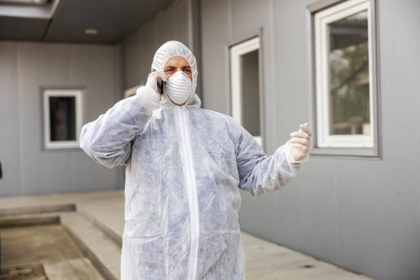 istock Man in virus protective suit and mask talking at smartphone mobi 1218756578