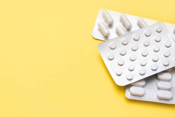 ampollas con píldoras blancas sobre un fondo de primavera amarillo con un espacio de copia - hormone therapy hrt pill medicine fotografías e imágenes de stock