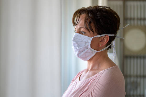 istock Woman wearing a face mask standing indoors 1218758677