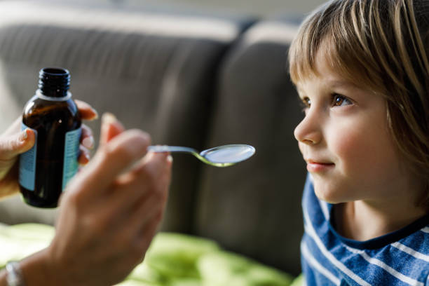 istock Small boy taking cough syrup from his parent at home. 1218758959