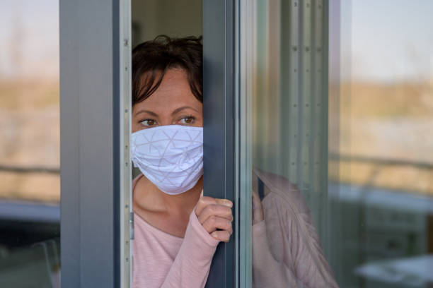 istock Woman wearing a face mask peering around anxiously 1218759271
