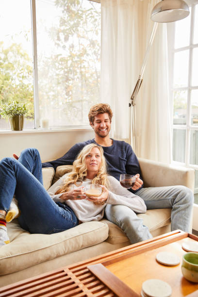 istock Smiling young couple drinking coffee while relaxing at home 1218760463